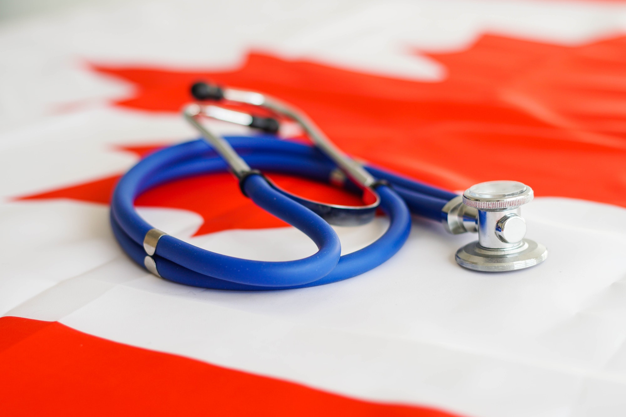 Medical stethoscope on a Canada flag. Canadian health care system, insurance.